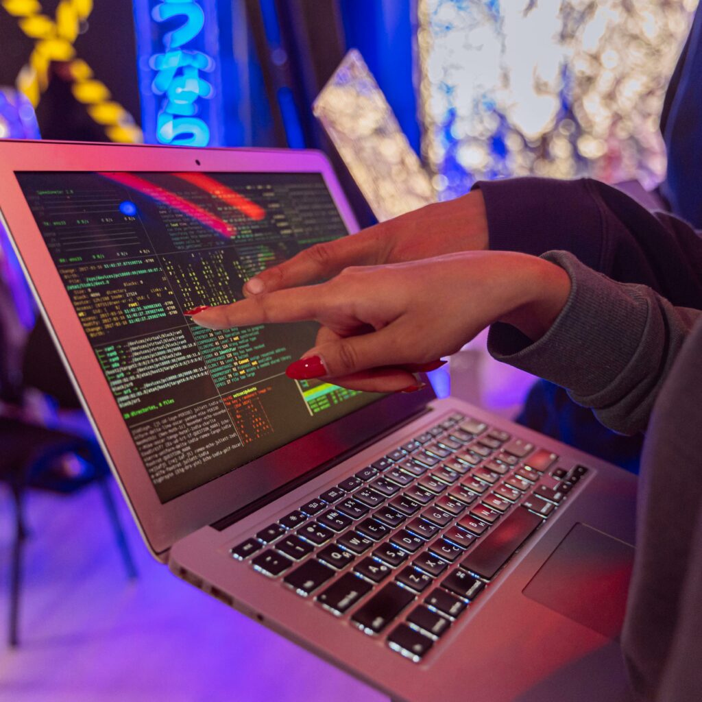 A vibrant scene with hands pointing at a computer with code on display, suggesting tech focus.