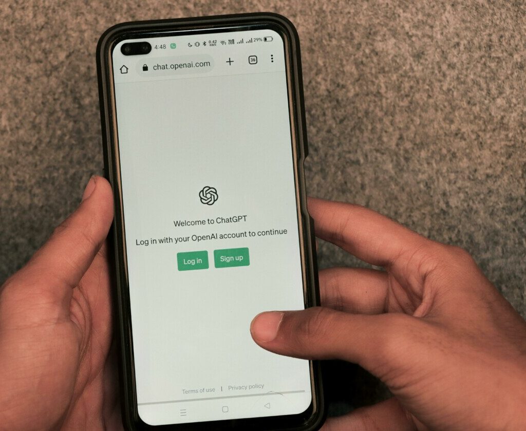 Close-up of hands using smartphone with ChatGPT app open on screen.